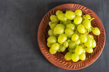 grape on brown plate on dark background with copy space