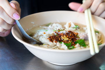 Noodle with hand of woman holding spoon and chopsticks.Selective focus