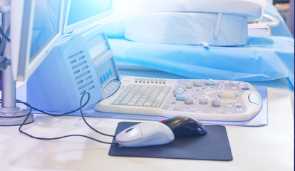 Close-up shot of medical ultrasound scanner with control bittons knobs sliders and ultrasonic transducer in background