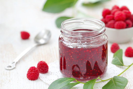 Raspberry jam in a jur and fresh berries on the table