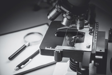 Close up of old vintage of microscope with metal lens and science equipment at laboratory research desk. School laboratory and classic microscope for students.