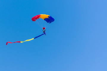 A Parachute with Romanian Flag Colours on a Clean Blue Background