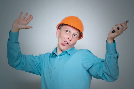 Perplexed crazy builder worker with mobile phone isolated on gray background.