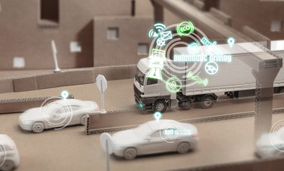 Weisser Spielzeug LKW auf einer Kartonautobahn simuliert Autonomes Fahren
