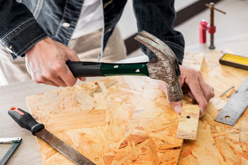 Carpenter working carefully looking at the plans work in carpentry. He is successful entrepreneur at his workplace. hammering a nail Supports On Building Site work with cutter.