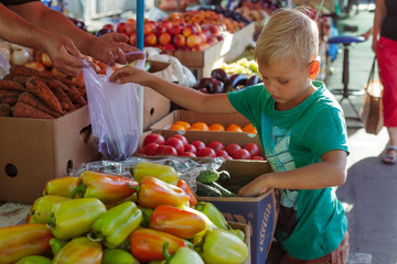Boy buying vegetables on market
