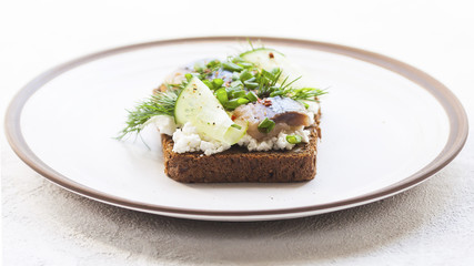 Sandwich with pieces of marinated herring with cream and dill. Selective focus.