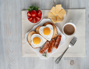 Breakfast with love - fried eggs in the shape of a heart, fried sausages and coffee