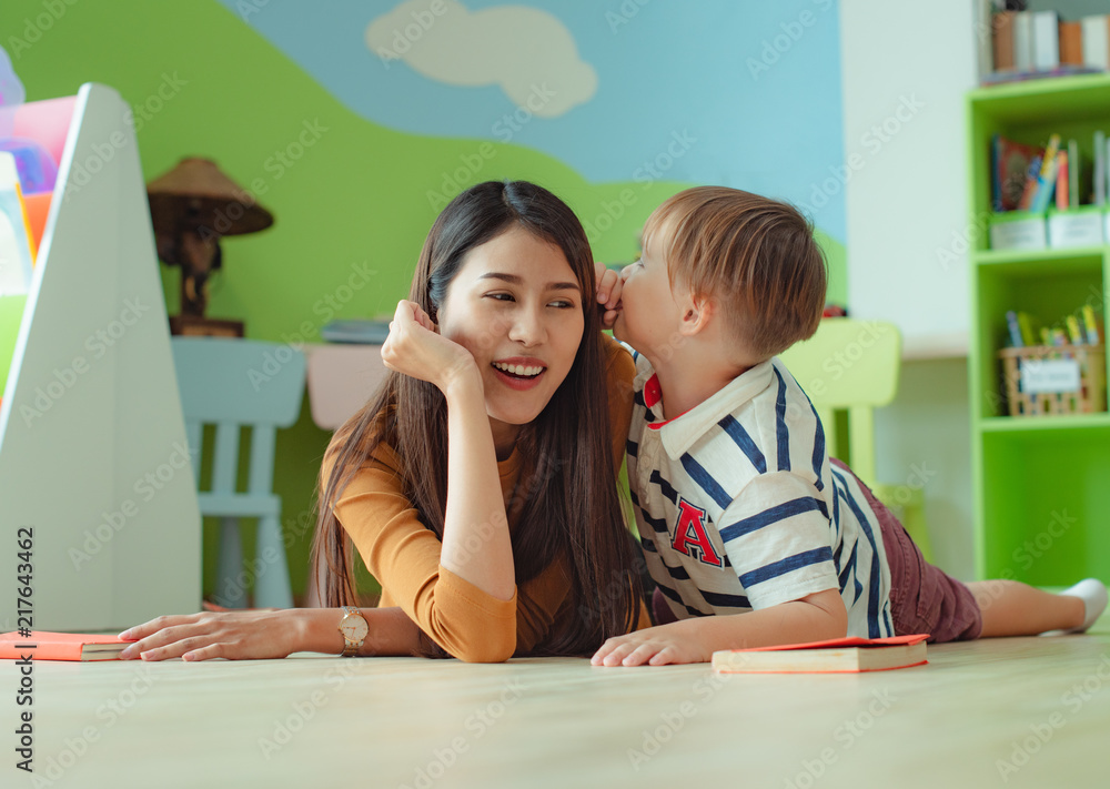 Wall mural woman listening a boy on coo or whispers in ear for some personal secret story telling