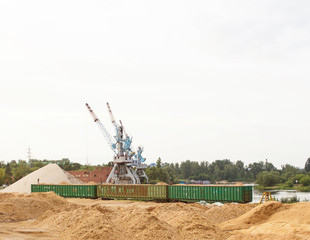 Fototapeta premium The port crane makes loading of wood chips into the freight cars of the train, loading