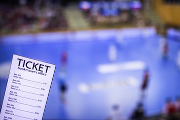 Bookmaker ticket on the background of the TV on which show handball, sports betting, handball