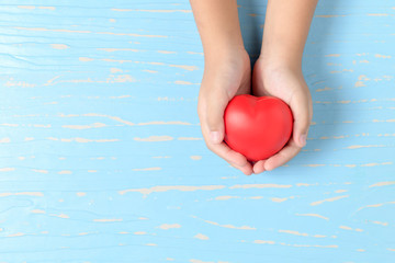 Fototapeta premium child hands holding red heart on blue wood