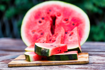 Slices and half of fresh watermelon on wooden board