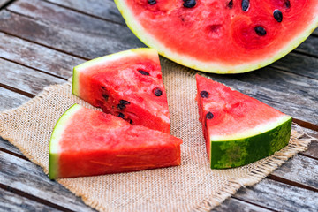 Slices and half of fresh watermelon on wooden board