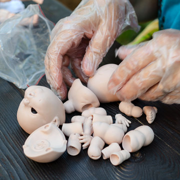 Female hands make dolls of BJD in the workplace. Processing the workpiece. The concept of the craft of the master manufacturer of dolls. Selective focus. For instagram format. Square.