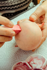 Female hands make dolls of BJD or reborn in the workplace. Processing the workpiece. The concept of...