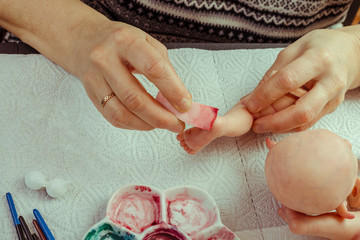 Female hands make dolls of BJD or reborn in the workplace. Processing the workpiece. The concept of...