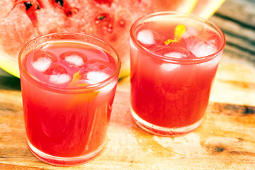 Watermelon slices and juice on wooden table