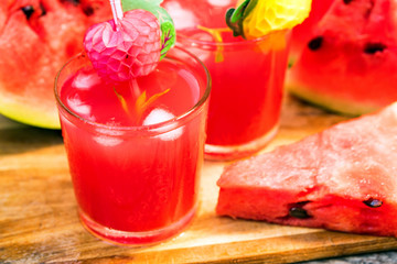 Watermelon slices and juice on wooden table