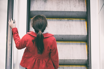 Woman commuter going to work walking up escalator stairs commuting in train station or airport.