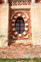 A fragment of an old brick wall with oval arch window guard - Russia, Mozhaisk Kremlin, region landmark Novo-Nikolsky Cathedral on a summer day