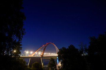 Bridge over the river Ob night. The lights of the bridge glow in the night sky.
