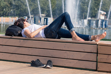 The girl is resting barefoot near the fountain in the park