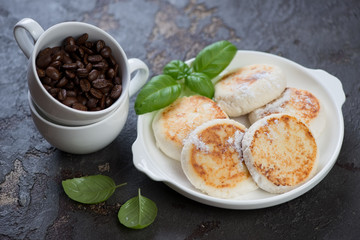 White plate with pan fried curd pancakes or syrniki and coffee beans, studio shot, selective focus