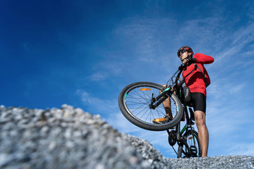 Young man riding mountain bike on the background of mountains at blue sky