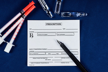 prescription, pen, syringes and three ampoules on a blue velvet background
