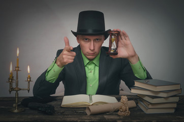Severe detective agent man in a bowler hat is sitting by the table and holding in hands a sand...
