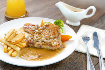 Juicy grilled pork steak and potatoes vegetables for restaurant menus healthy eating homemade with mushroom sauce on wooden table.