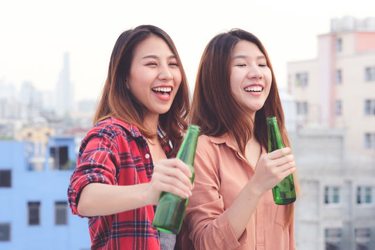 Two asian women drinking at rooftop party, outdoors celebration, LGBT couple