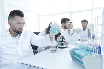 biochemist with flask Petri sitting at a Desk