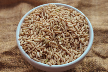 Raw brown rice in a bowl. top view food background