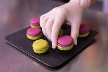 Black plate. Master of confectionary feeling satisfied while putting nice bright macaroons on black plate