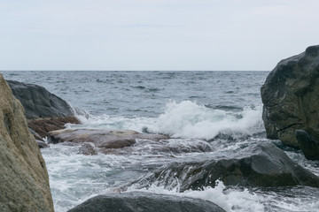 Waves are beating against rocks on the seashore, the ocean in cloudy weather.