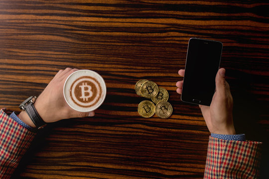 Businessman with phone and bitcoin coffee.