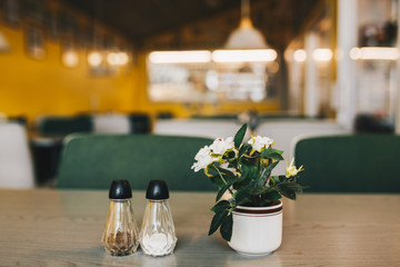 Cafe interior. Close up of a table with vase with flowers. Blurry background.