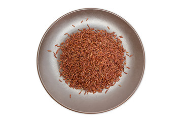 Uncooked red rice on the brown dish on white background