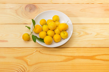 Yellow cherry plums on saucer on a wooden surface