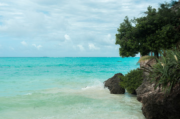 Turquoise waves of the Indian ocean run on the white beach of the island of Zanzibar