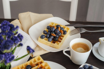 Belgian waffle decorated  with blueberries and nuts, open book on wooden table for perfect  breakfast at Sunday. Homemade dessert background. Relax moments concept.