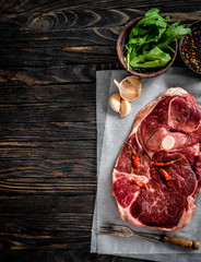 Piece of raw lamb meat with spices on dark wooden table, top view