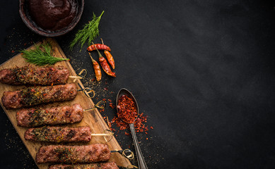 Grilled kebab with spices and sauce on a dark background