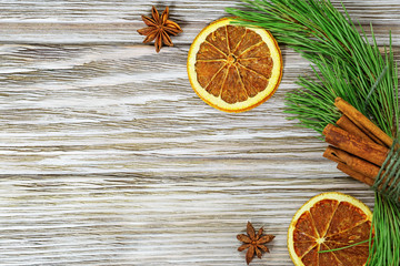 Christmas decoration. New Year concept. Cinnamon sticks, dried orange slices,   branch of pine on wooden background. Copy space.