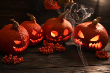 halloween pumpkin lanterns with luminous scary faces on a dark background with the smoke around them