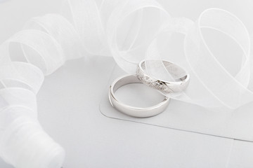 Two silver wedding rings with diamonds on gray background