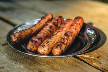 Sausages cooking on grill served on a plate. Food background with barbecue party, front view