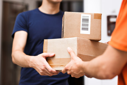 A person wearing an orange T-shirt is delivering parcels to a satisfied client. Friendly worker, high quality delivery service.